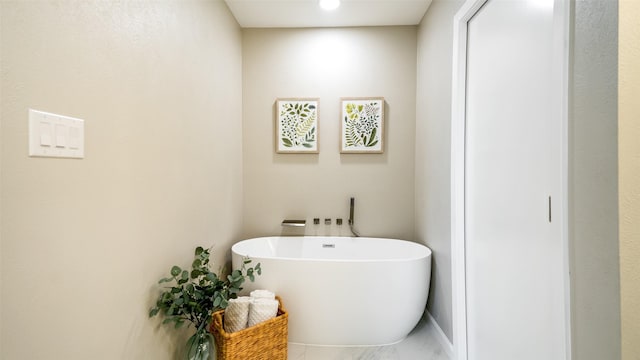 full bathroom featuring marble finish floor and a freestanding bath