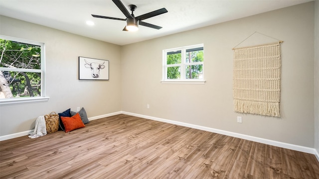 spare room with a healthy amount of sunlight, ceiling fan, baseboards, and wood finished floors