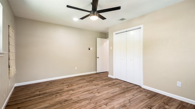 unfurnished bedroom featuring a closet, visible vents, a ceiling fan, wood finished floors, and baseboards