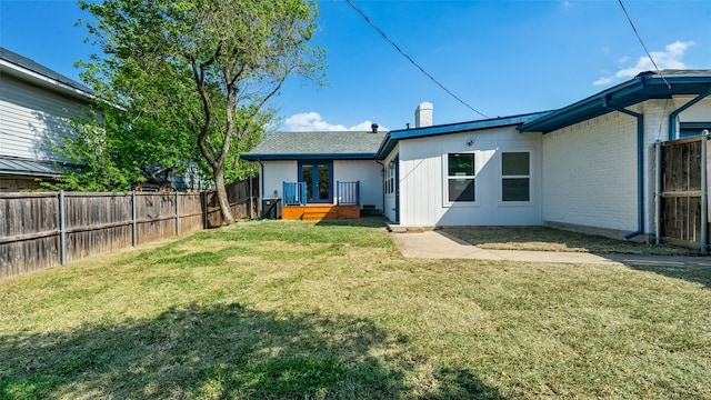 rear view of house featuring brick siding, a yard, and a fenced backyard