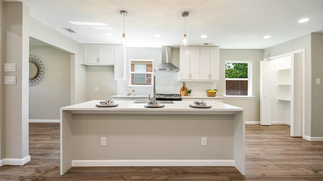 kitchen with white cabinetry, wall chimney exhaust hood, visible vents, and light wood-style flooring