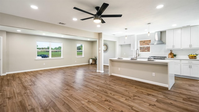 kitchen featuring recessed lighting, open floor plan, white cabinets, wood finished floors, and wall chimney exhaust hood