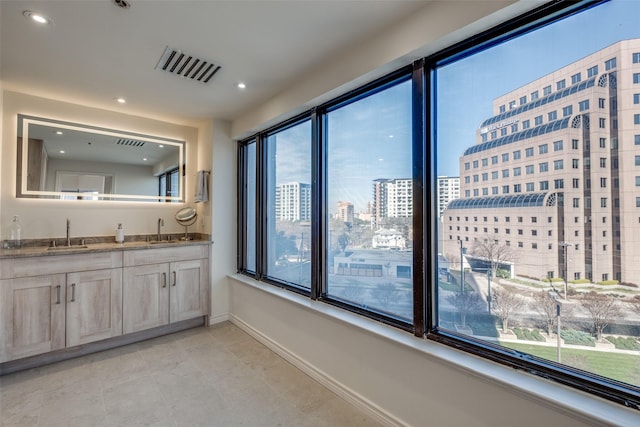 bathroom featuring visible vents, a city view, baseboards, and a sink