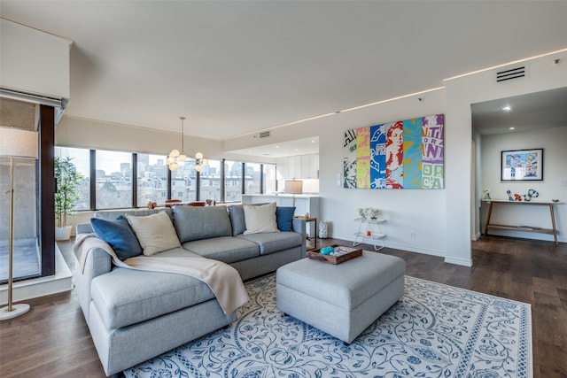 living room featuring a wealth of natural light, visible vents, a notable chandelier, and wood finished floors