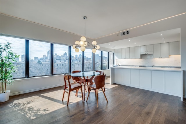 dining space featuring visible vents, a view of city, baseboards, a chandelier, and dark wood-style flooring