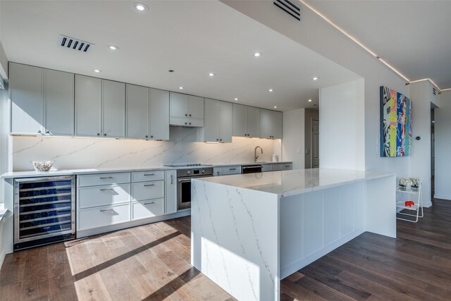 kitchen with stainless steel oven, wine cooler, wood finished floors, and visible vents