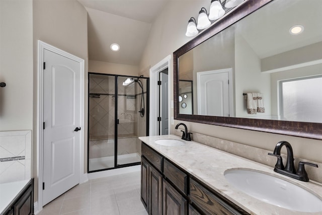 bathroom with vaulted ceiling, a stall shower, a sink, and tile patterned floors