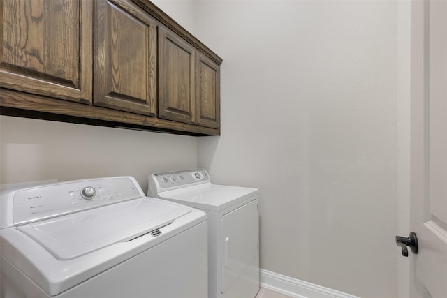 clothes washing area featuring cabinet space, baseboards, and separate washer and dryer