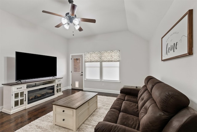 living area featuring vaulted ceiling, dark wood finished floors, baseboards, and ceiling fan