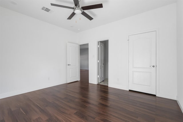 unfurnished bedroom featuring visible vents, baseboards, a ceiling fan, dark wood-type flooring, and a spacious closet