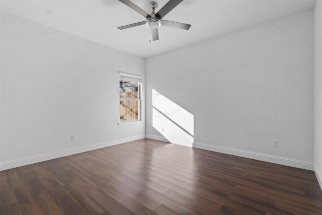 empty room with a ceiling fan, dark wood finished floors, and baseboards