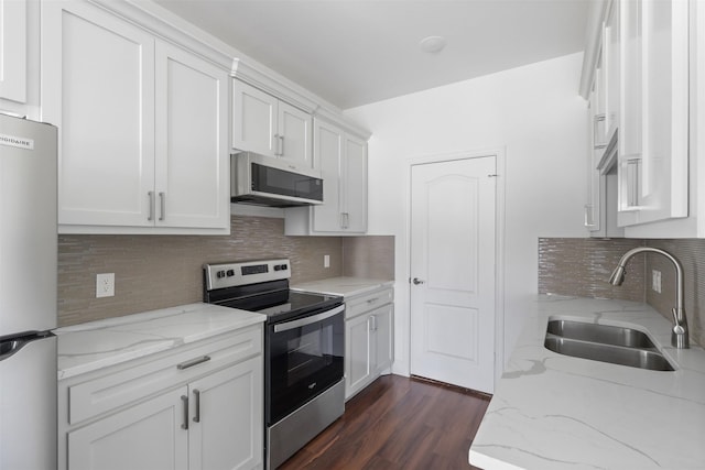 kitchen with dark wood-style flooring, light stone countertops, stainless steel appliances, white cabinetry, and a sink