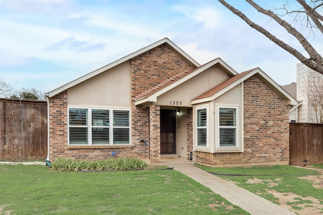 view of front facade with brick siding, a front yard, fence, and stucco siding