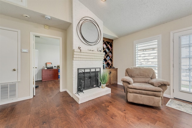 sitting room featuring vaulted ceiling, a fireplace, visible vents, and a healthy amount of sunlight