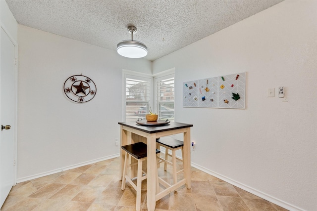 dining area with baseboards and a textured ceiling