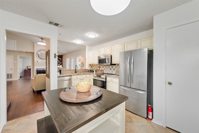 kitchen featuring visible vents, appliances with stainless steel finishes, tasteful backsplash, and cream cabinetry