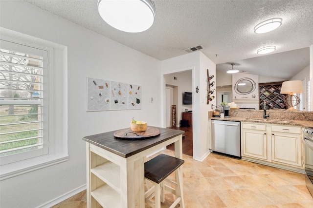 kitchen with visible vents, cream cabinets, stove, a sink, and dishwasher