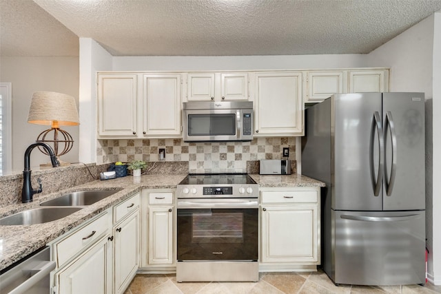 kitchen featuring light stone countertops, appliances with stainless steel finishes, decorative backsplash, and a sink