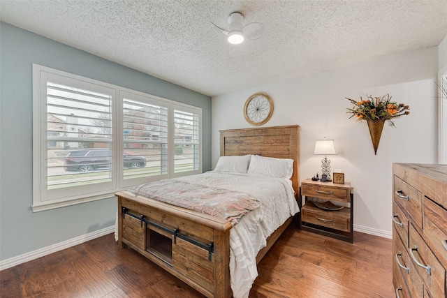 bedroom with dark wood-style floors, a textured ceiling, and baseboards