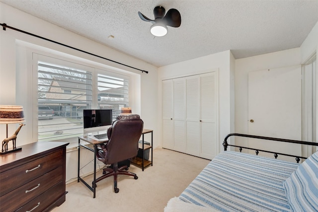 bedroom with a textured ceiling, a closet, and light colored carpet