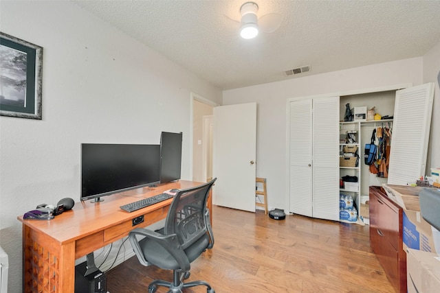 office with a textured ceiling, visible vents, and wood finished floors