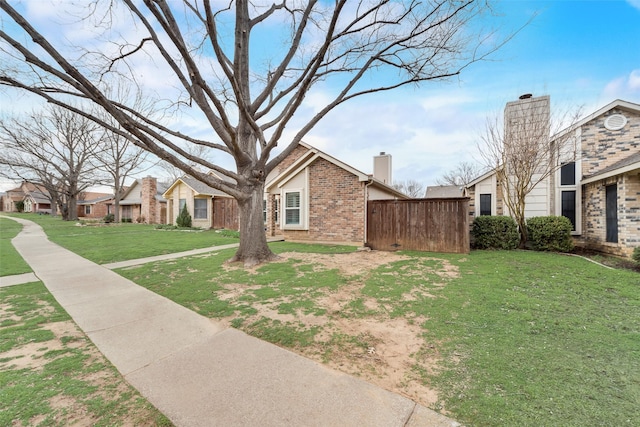 view of property exterior with brick siding, a chimney, a lawn, fence, and a residential view