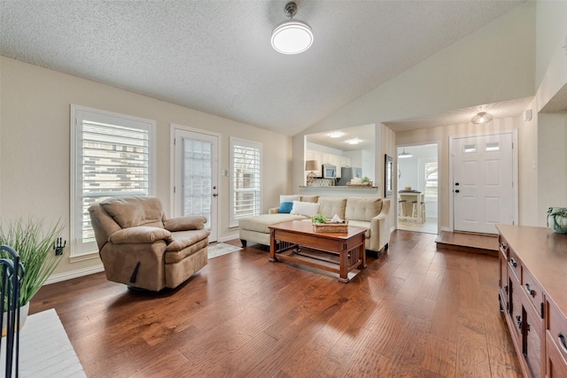 living room with dark wood-type flooring, lofted ceiling, a textured ceiling, and baseboards