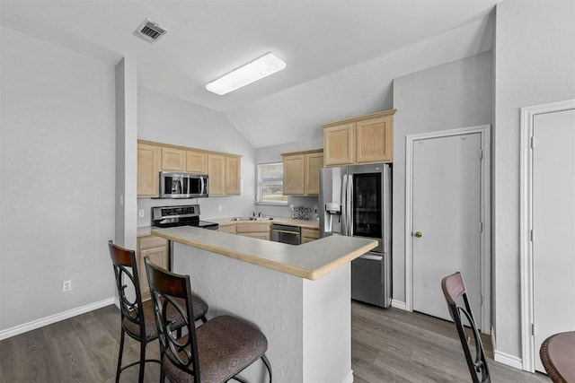 kitchen with a sink, a kitchen breakfast bar, light brown cabinetry, and stainless steel appliances