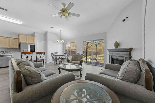 living room featuring light wood finished floors, visible vents, lofted ceiling, ceiling fan with notable chandelier, and a fireplace