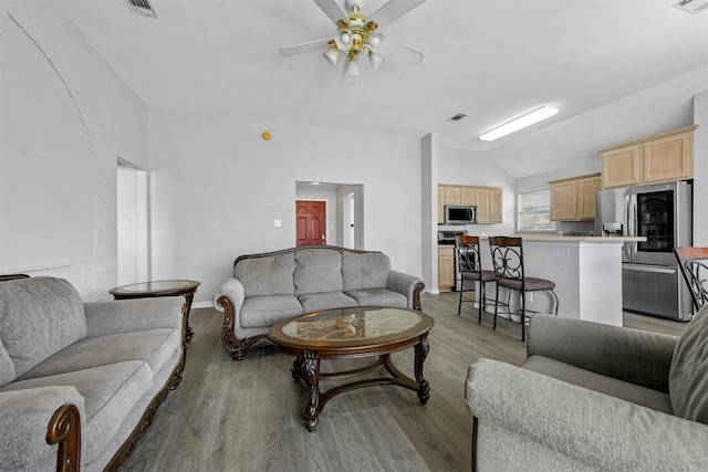 living area with light wood-type flooring, lofted ceiling, visible vents, and ceiling fan