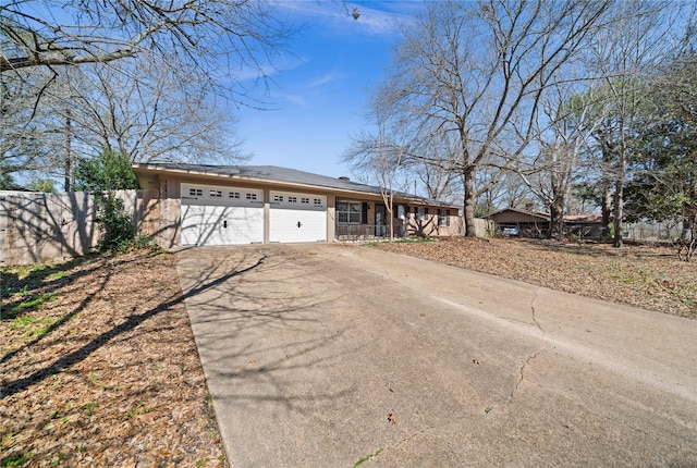 view of front of property featuring a garage, fence, and concrete driveway