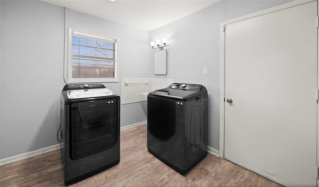 laundry room with laundry area, baseboards, light wood finished floors, and separate washer and dryer