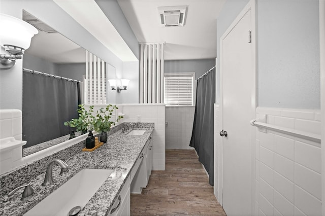 full bathroom with visible vents, a sink, tile walls, and wood finished floors