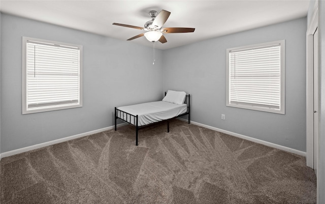 unfurnished bedroom with carpet flooring, a ceiling fan, and baseboards