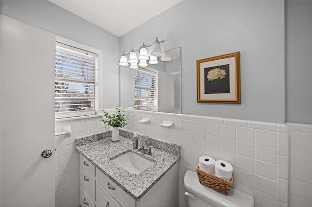 half bathroom with wainscoting, tile walls, toilet, and vanity