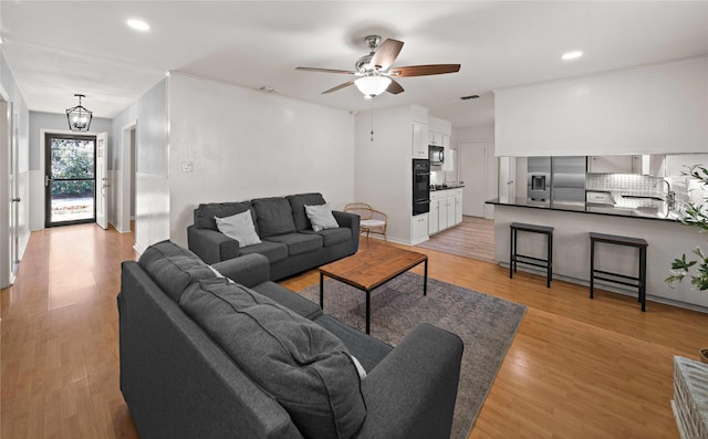 living room featuring ceiling fan with notable chandelier, recessed lighting, visible vents, and light wood-style floors