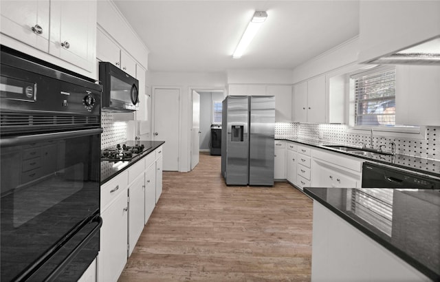 kitchen featuring black appliances, a wealth of natural light, backsplash, and a sink