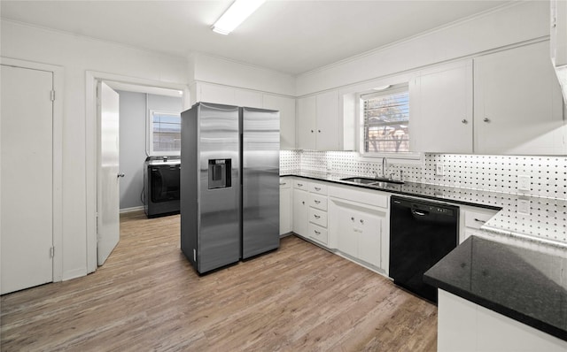 kitchen with dark countertops, black dishwasher, stainless steel fridge, and a sink