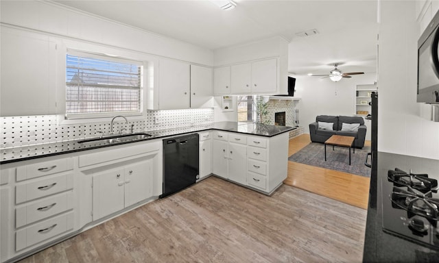 kitchen featuring dark countertops, backsplash, light wood-style flooring, a sink, and black appliances