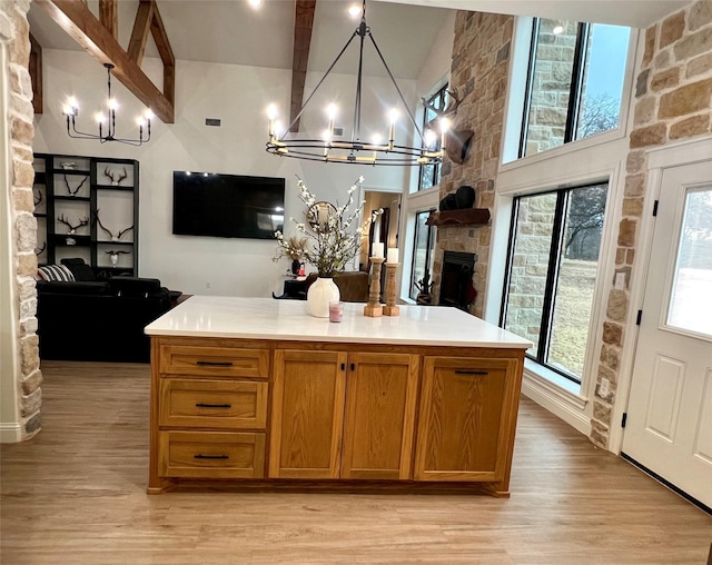 kitchen featuring a center island, an inviting chandelier, light countertops, light wood-style floors, and a fireplace