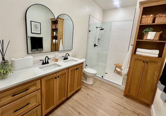 bathroom with a stall shower, vanity, toilet, and wood finished floors