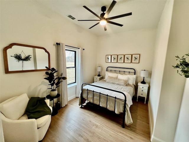 bedroom featuring a ceiling fan, visible vents, baseboards, and wood finished floors