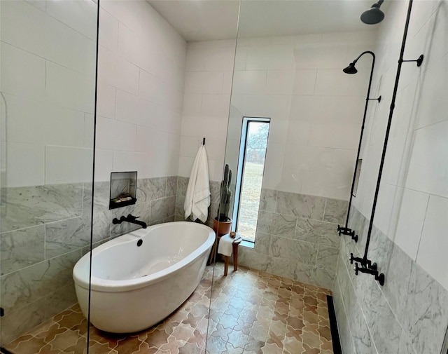 bathroom with a freestanding tub, stone finish floor, walk in shower, and tile walls