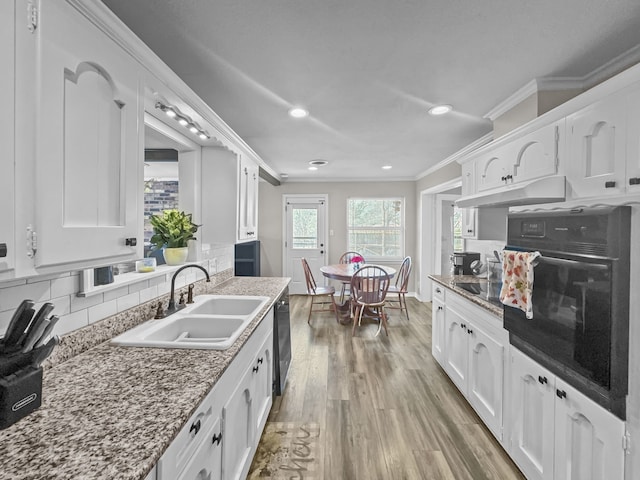 kitchen featuring under cabinet range hood, white cabinets, black appliances, and a sink