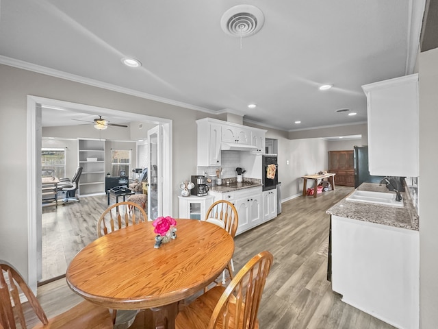 dining space featuring visible vents, crown molding, and light wood-style floors