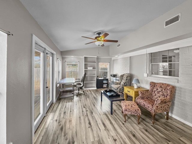 sitting room featuring a ceiling fan, vaulted ceiling, wood finished floors, and visible vents