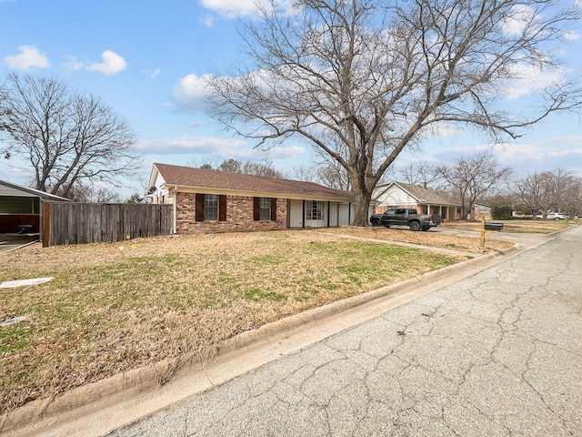 view of front of home featuring a front lawn, fence, and brick siding