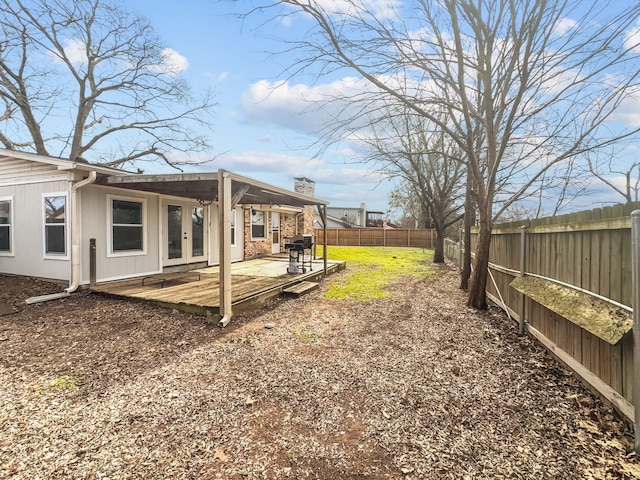 view of yard with a fenced backyard, french doors, and a wooden deck