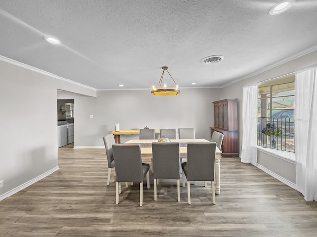 dining room with visible vents, washer and dryer, crown molding, and wood finished floors