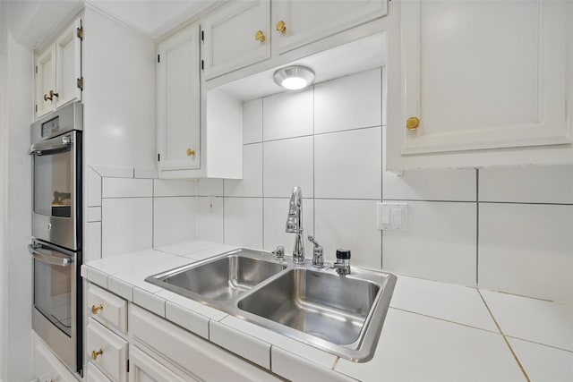 3620 Red Oak Dr, Corinth, TX 76208 - kitchen featuring a sink, double oven, white cabinetry, backsplash, and tile countertops